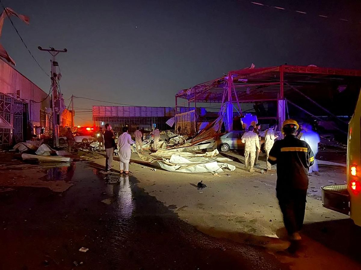 Residents and civil defence officials stand near cars and buildings damaged by shrapnel from the intercepted ballistic missile that landed in an industrial area, in south of Dhahran, Saudi Arabia, January 24, 2022. Saudi Press Agency/Handout via REUTERS
